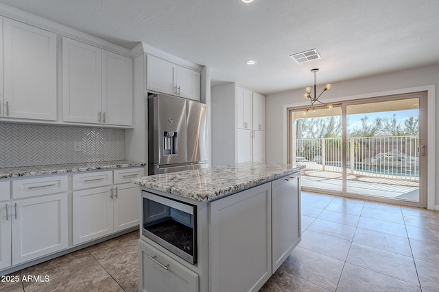 kitchen with white cabinets, appliances with stainless steel finishes, tasteful backsplash, and hanging light fixtures