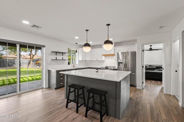 kitchen featuring white cabinetry, hardwood / wood-style floors, a kitchen island, and appliances with stainless steel finishes