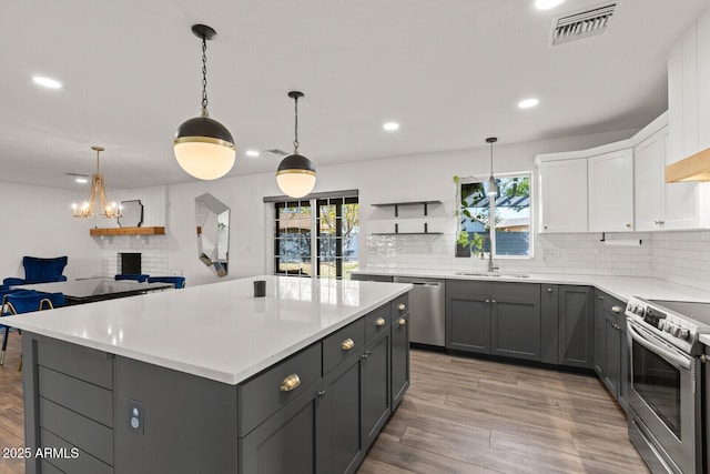 kitchen with gray cabinetry, pendant lighting, white cabinetry, and stainless steel appliances