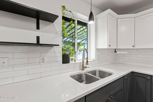 kitchen with decorative backsplash, white cabinetry, sink, and decorative light fixtures