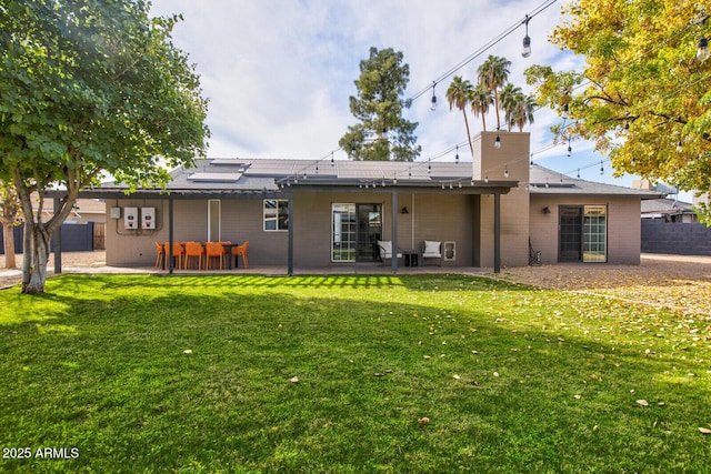 rear view of house featuring solar panels, a patio area, and a lawn