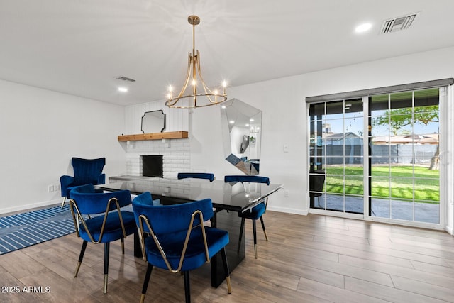 dining space featuring hardwood / wood-style floors, a fireplace, and an inviting chandelier