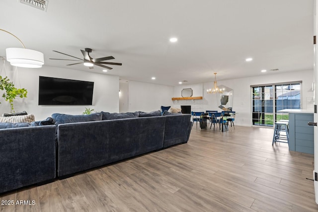 living room with ceiling fan with notable chandelier and hardwood / wood-style flooring