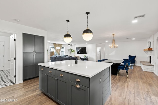 kitchen featuring gray cabinetry, a center island, light hardwood / wood-style floors, and a brick fireplace