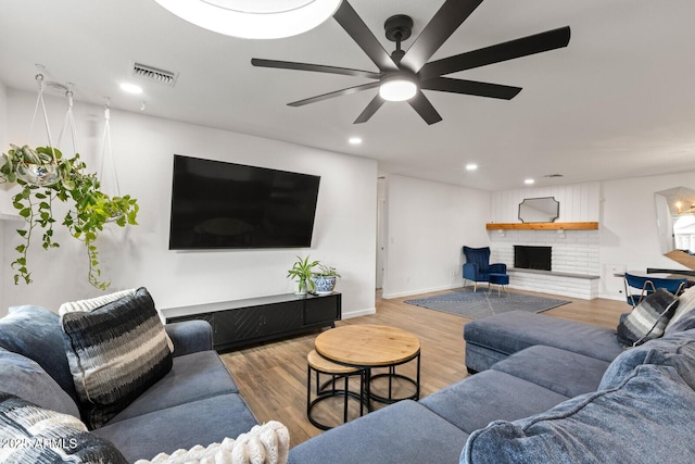 living room featuring ceiling fan, wood-type flooring, and a fireplace