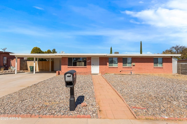 ranch-style house featuring a carport, brick siding, and driveway