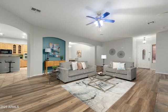 living room featuring light wood-style floors, arched walkways, and visible vents