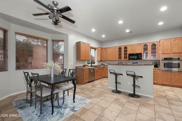 kitchen featuring recessed lighting, appliances with stainless steel finishes, glass insert cabinets, a sink, and a kitchen island