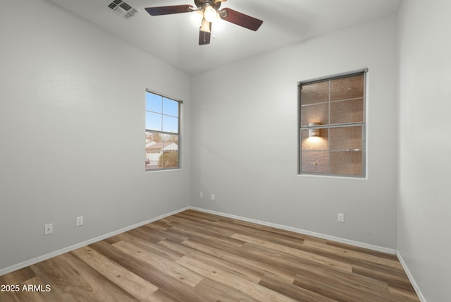 empty room featuring baseboards, visible vents, ceiling fan, and wood finished floors