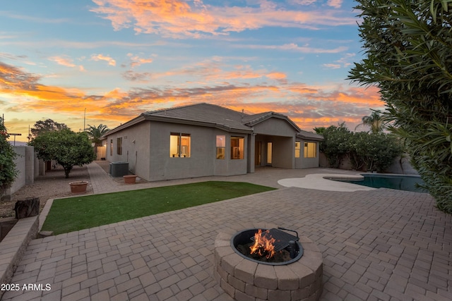 rear view of house featuring central AC unit, a fire pit, a patio, a fenced backyard, and stucco siding