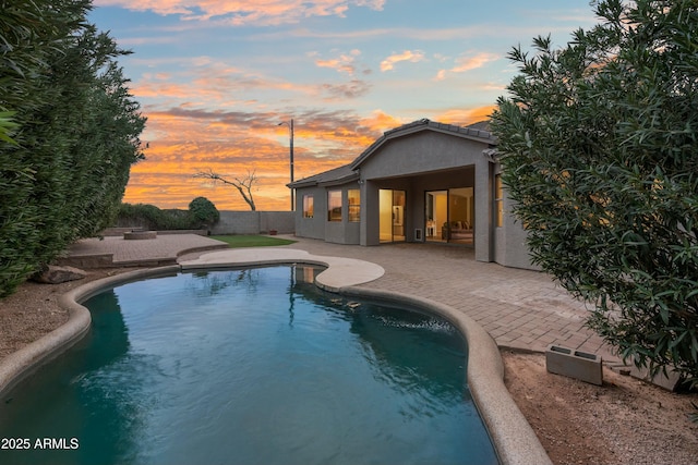 pool at dusk featuring a patio, a fenced backyard, and a fenced in pool