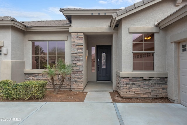 view of exterior entry featuring stone siding and stucco siding