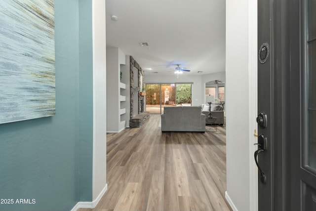 entrance foyer with ceiling fan, a fireplace, wood finished floors, visible vents, and baseboards