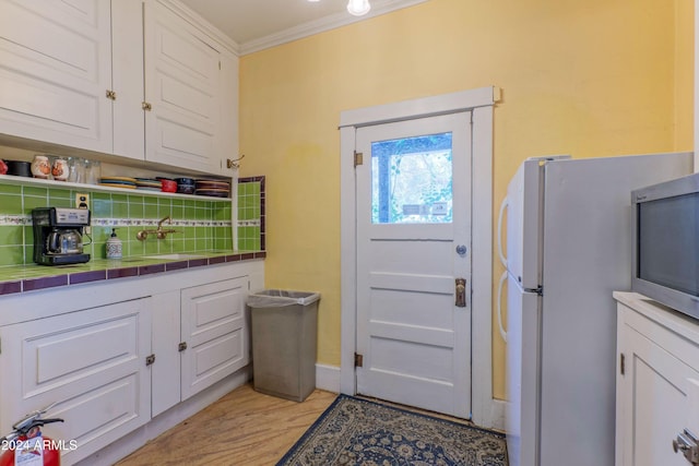 entryway with sink, light wood-type flooring, and ornamental molding