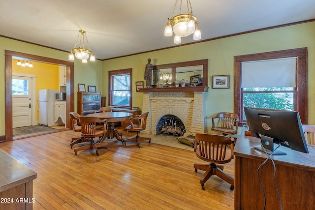 office area with light hardwood / wood-style flooring, a chandelier, plenty of natural light, and a brick fireplace