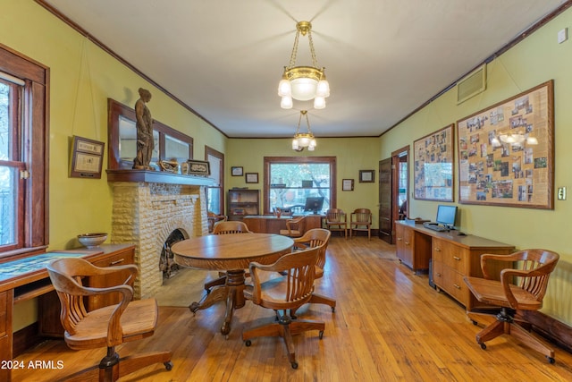 dining area featuring a fireplace, light hardwood / wood-style flooring, an inviting chandelier, and crown molding