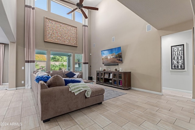 living room featuring ceiling fan, a towering ceiling, and light hardwood / wood-style flooring