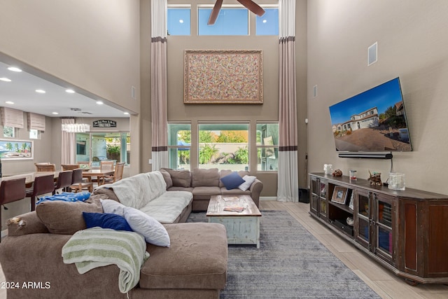 tiled living room with ceiling fan and a high ceiling