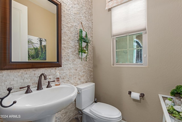 bathroom featuring decorative backsplash, toilet, and sink