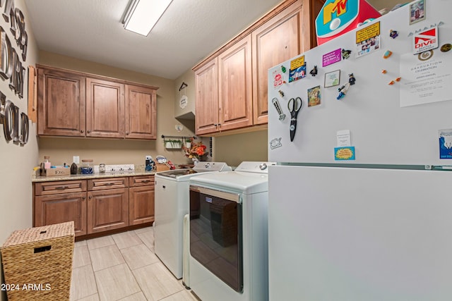 clothes washing area featuring washer and dryer, cabinets, and a textured ceiling