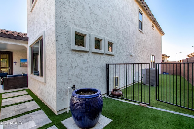 view of property exterior with central air condition unit and a yard