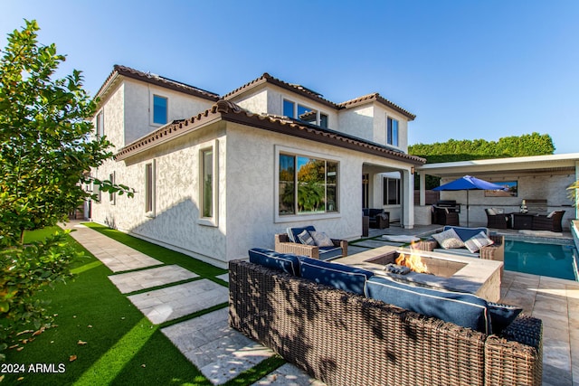 rear view of property featuring a patio area and an outdoor living space with a fire pit