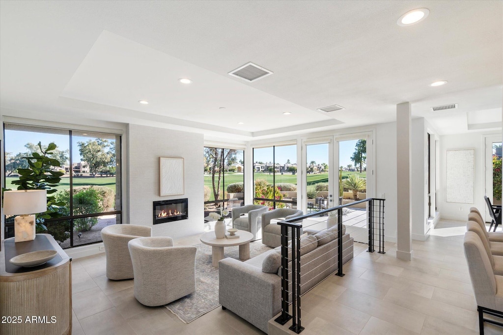 living room featuring plenty of natural light, a raised ceiling, and a fireplace