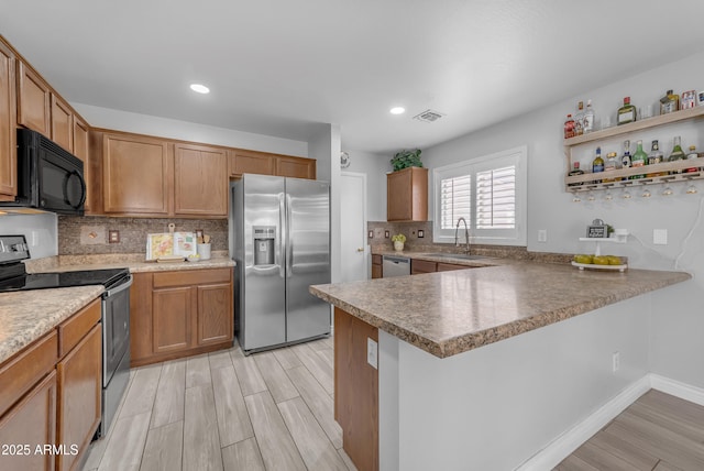 23693 W Grove St, Buckeye, AZ 85326 - kitchen featuring stainless steel appliances, a sink, light wood finished floors, backsplash, and a peninsula