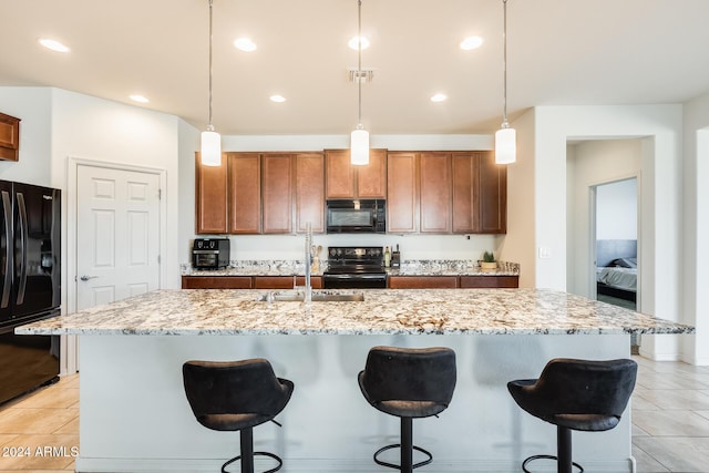 kitchen featuring pendant lighting, black appliances, a center island with sink, sink, and light tile patterned floors