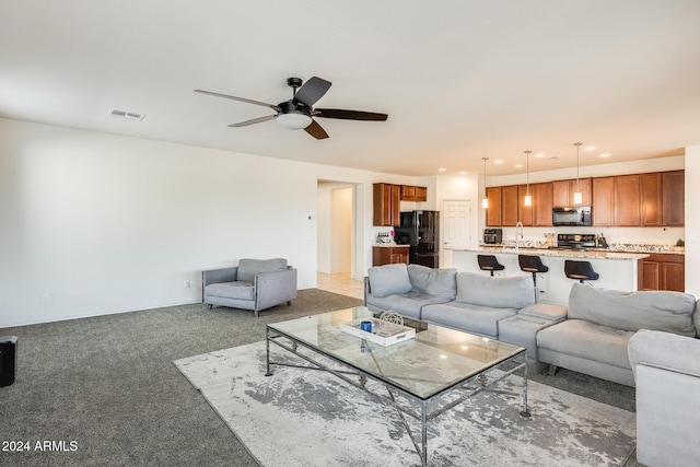 living room featuring ceiling fan, sink, and carpet floors