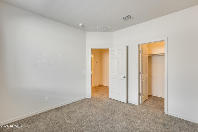 unfurnished bedroom with light carpet, a closet, and a spacious closet