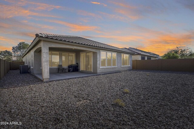 back house at dusk featuring a patio and central AC