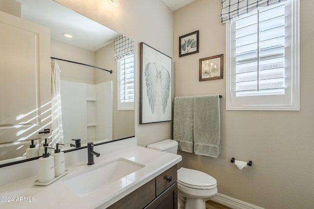 bathroom with walk in shower, vanity, and toilet