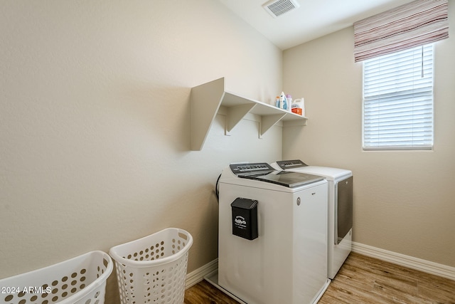 laundry room with separate washer and dryer and light hardwood / wood-style flooring