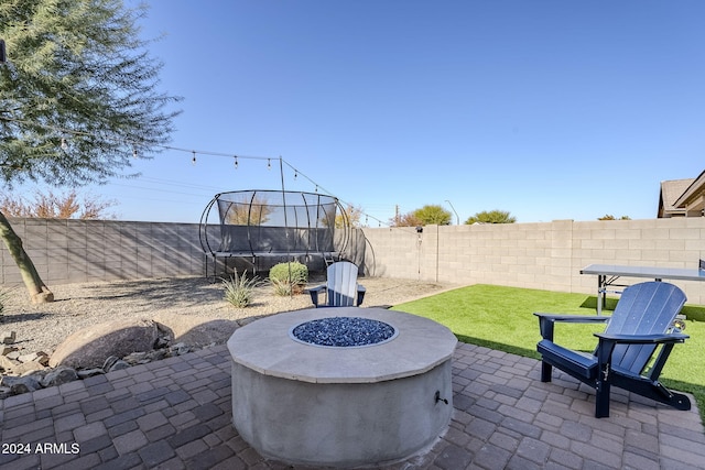 view of patio / terrace with a trampoline and an outdoor fire pit