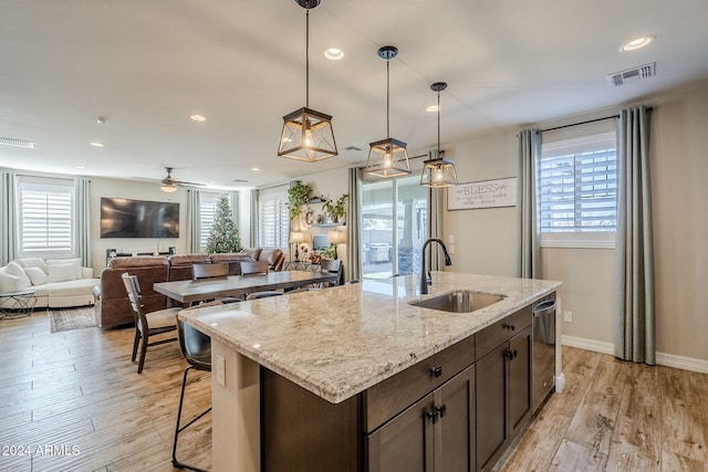 kitchen featuring ceiling fan, sink, light stone counters, light hardwood / wood-style flooring, and pendant lighting