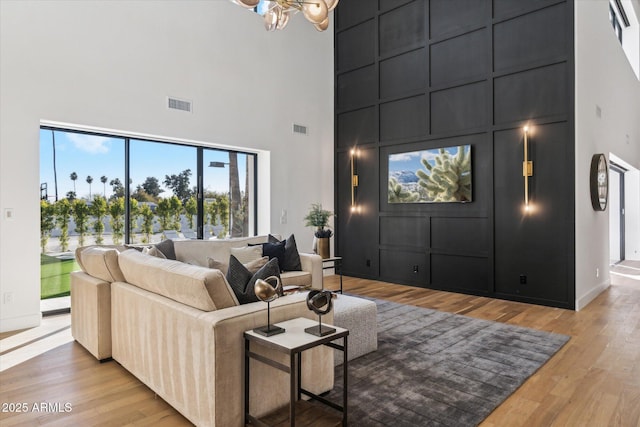 living room with light hardwood / wood-style floors, a towering ceiling, and a chandelier