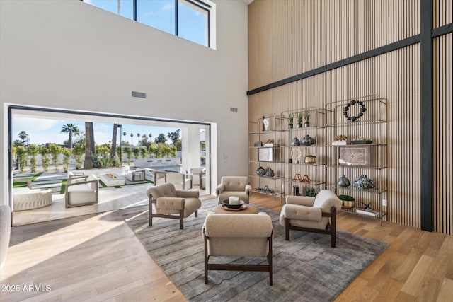 living room featuring a towering ceiling and light hardwood / wood-style flooring