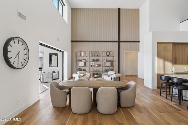 dining room featuring a towering ceiling and light hardwood / wood-style floors