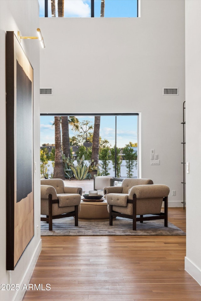 living room with a towering ceiling and wood-type flooring