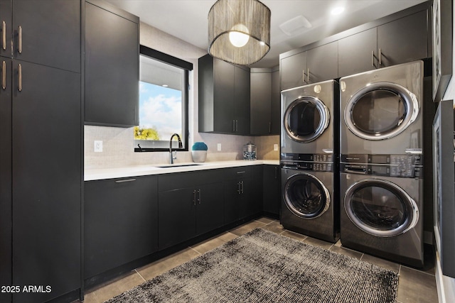 clothes washing area featuring sink, stacked washing maching and dryer, and cabinets