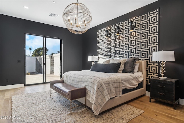 bedroom featuring light wood-type flooring, a chandelier, and access to exterior