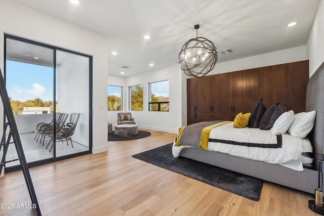 bedroom with an inviting chandelier, light hardwood / wood-style flooring, and access to exterior