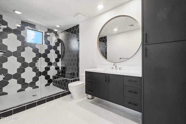 bathroom featuring vanity, a tile shower, tile patterned floors, and toilet