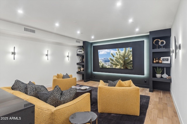 cinema room with built in shelves and light wood-type flooring