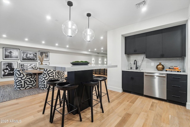 kitchen featuring sink, light hardwood / wood-style flooring, decorative light fixtures, and stainless steel dishwasher