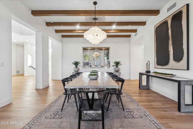 dining area with a notable chandelier, light hardwood / wood-style flooring, and beam ceiling