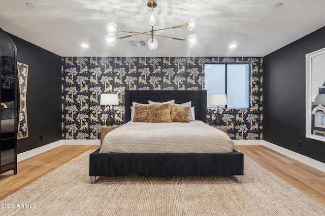 bedroom with wood-type flooring and an inviting chandelier