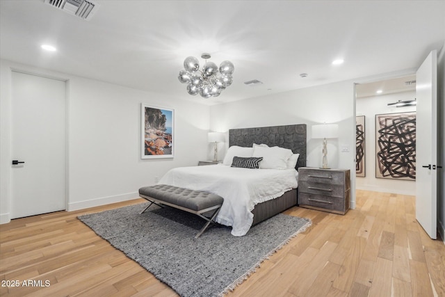 bedroom with light wood-type flooring and an inviting chandelier