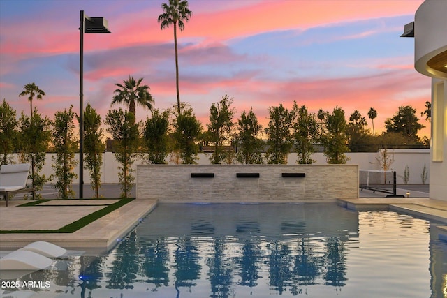 pool at dusk featuring a patio area